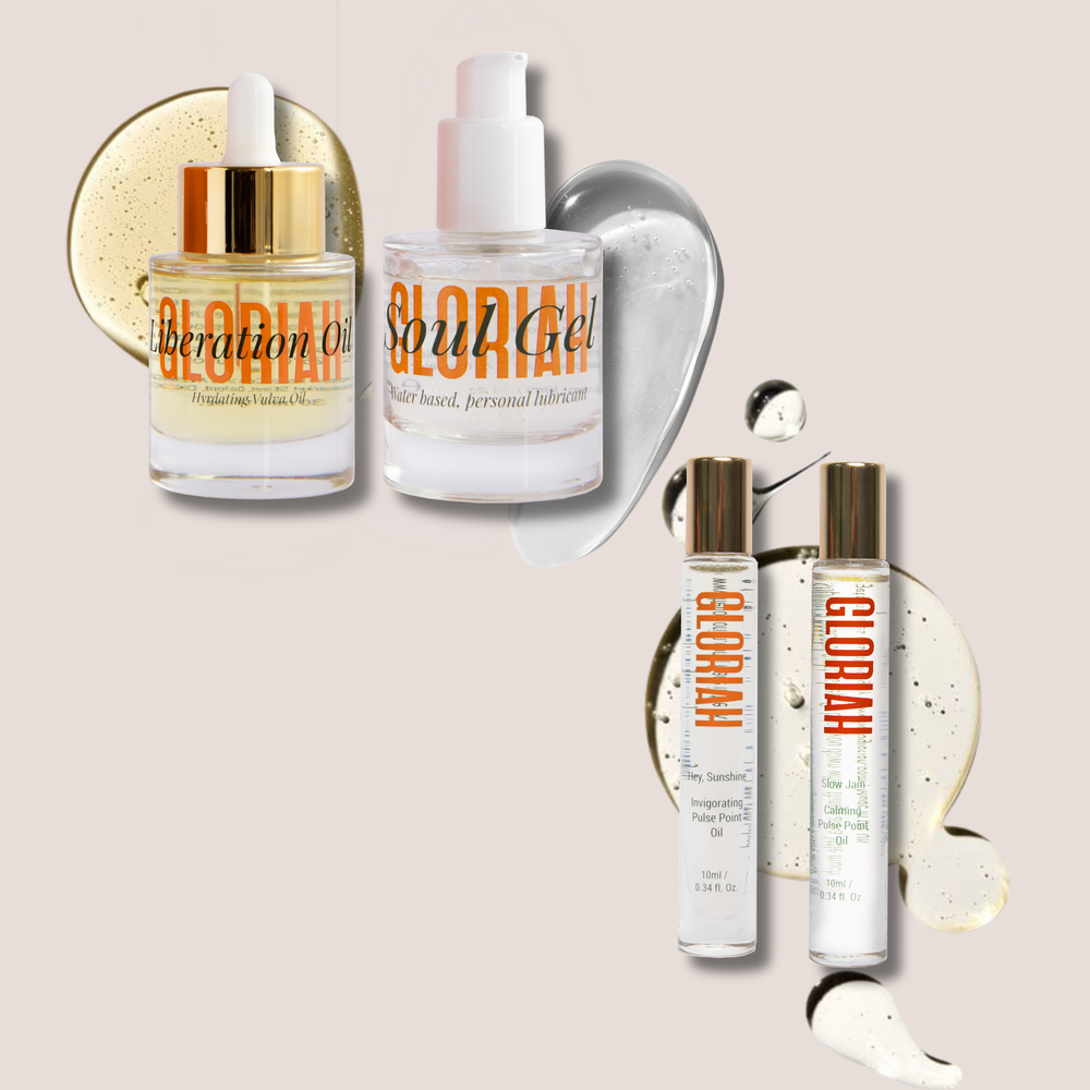 Four GLORIAH skincare bottles and tubes arranged on a light beige background with decorative gel and gold foil accents. The set includes a dropper bottle of liberation oil, a pump bottle of Soul gel, and two small roller bottles with gold caps.