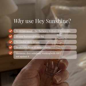 A hand holds a clear glass rollerball bottle labeled Hey Sunshine hormone-free pulse oil against a softly blurred warm indoor background. White text overlays read 'Why use Hey Sunshine?' with check marks and benefit points.