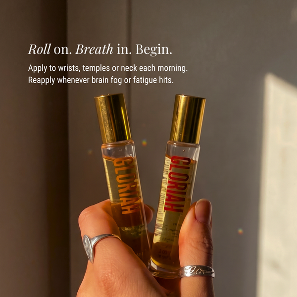 A hand holding two small clear roll-on perfume bottles with gold caps, against a warm-toned indoor background with text describing their use.