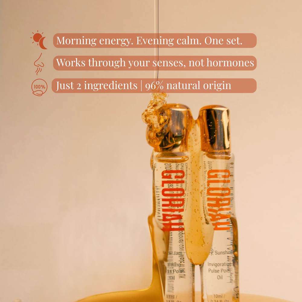 Two clear cosmetic bottles with metallic rose-gold caps and orange 'GLORIAH' branding, shown on a light beige background with decorative cream swirls and a small droplet.